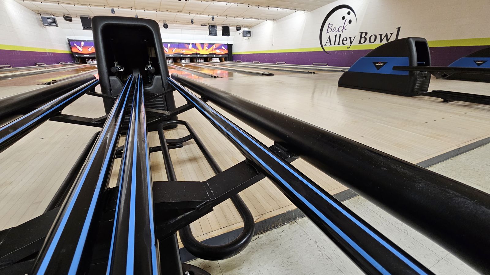Ball return and approach at Back Alley Bowl, with the logo on the wall