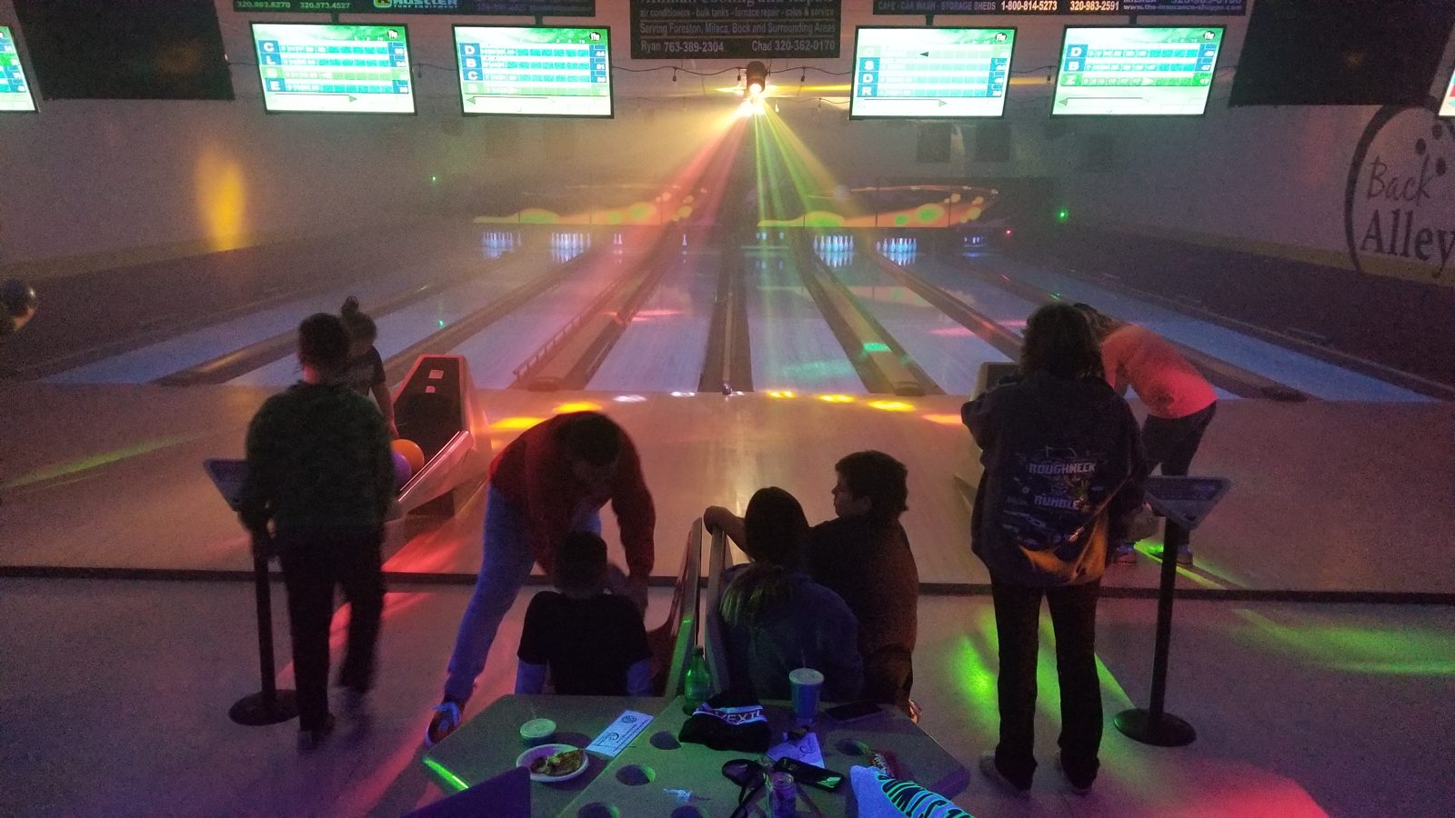 Cosmic Bowling with colored light beams and fog over the lanes
