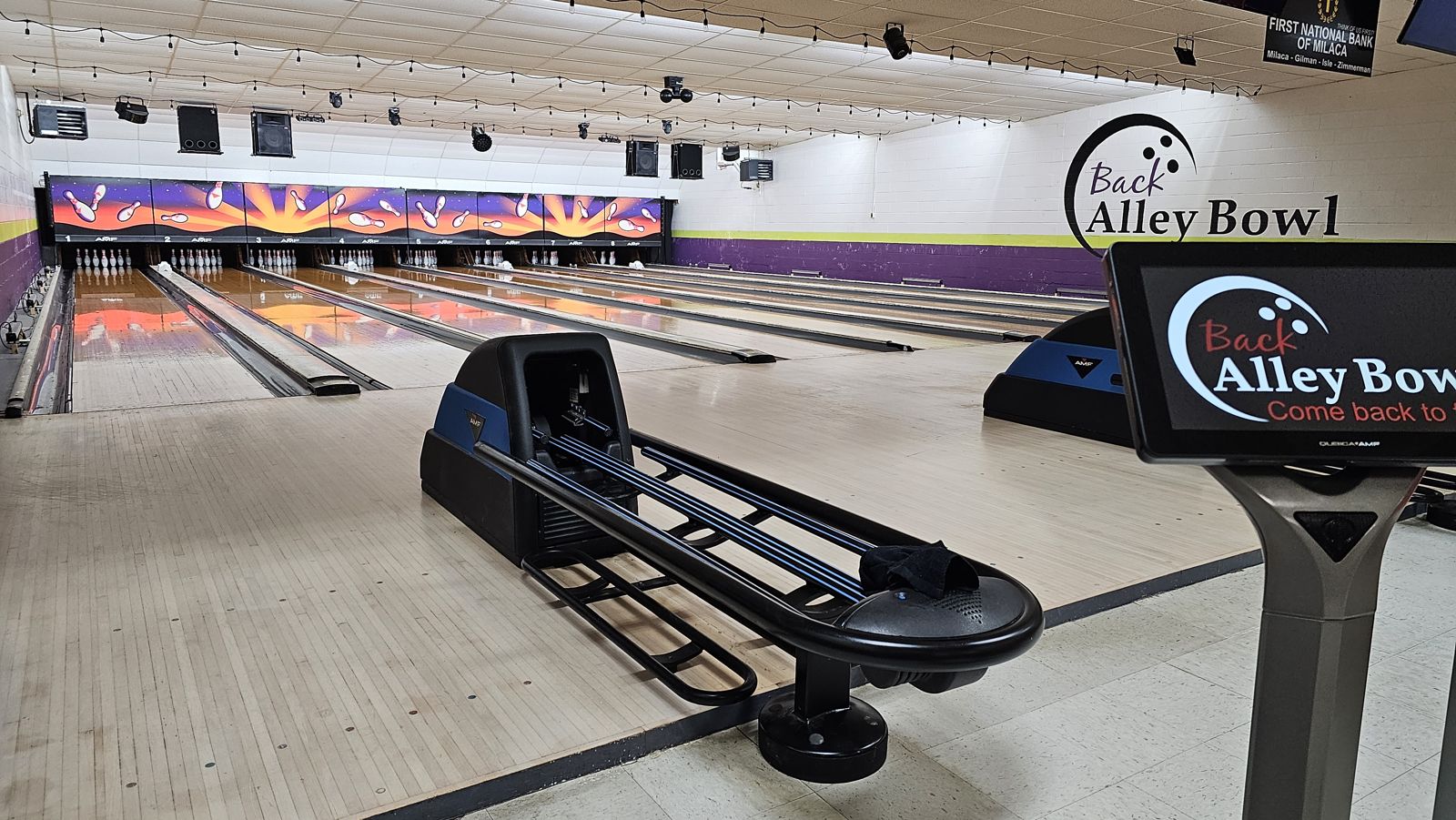 All eight lanes at Back Alley Bowl, with the pinsetter artwork glowing at the far end