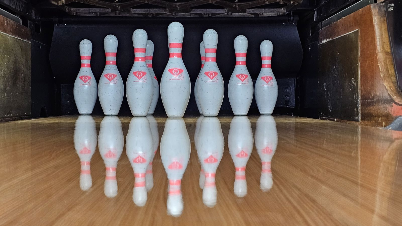 A full rack of ten pins reflected on a freshly oiled lane